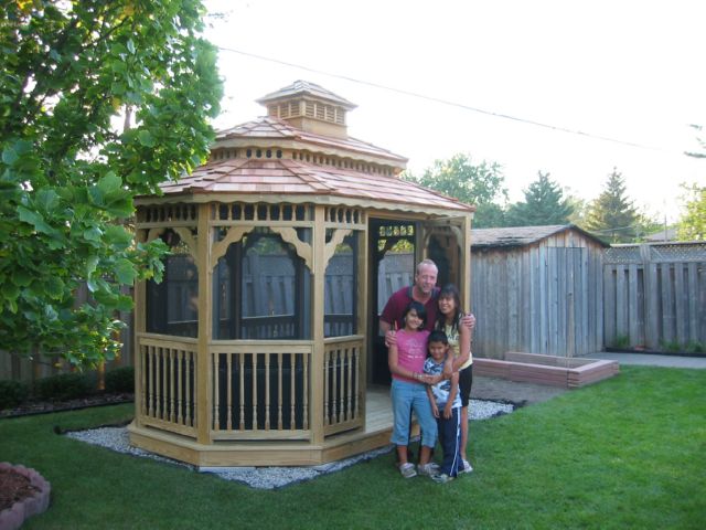 8 by 14 foot wooden oval gazebo with happy family standing in the front